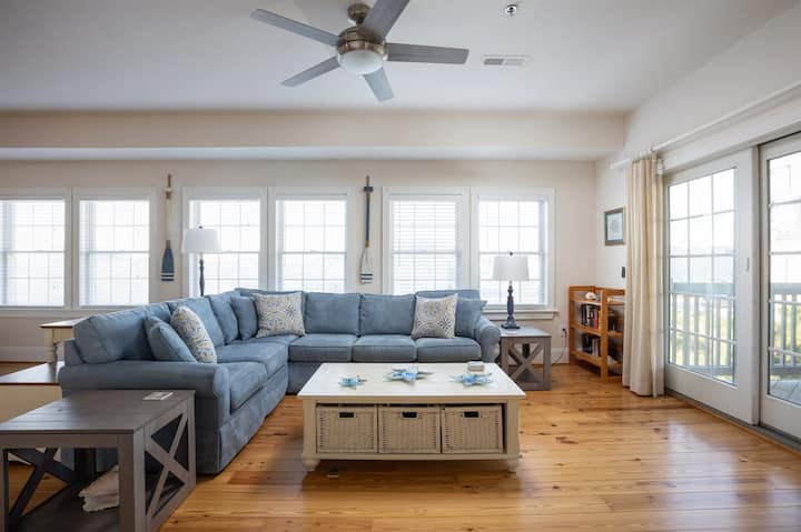 Sala de estar abierta con luz natural y cómodos espacios de reunión (con sofá cama, TV, barra de sonido y ventilador de techo)