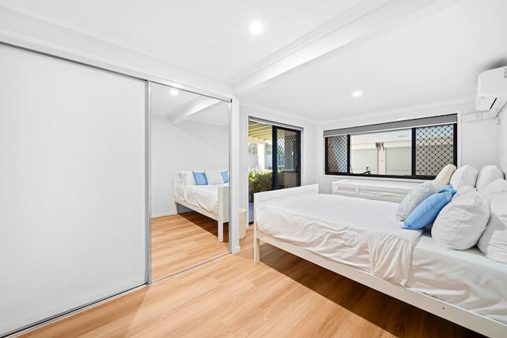 Svijetla spavaća soba s jednim bračnim krevetom i jednim jednostrukim krevetom sa svježom bijelom posteljinom.