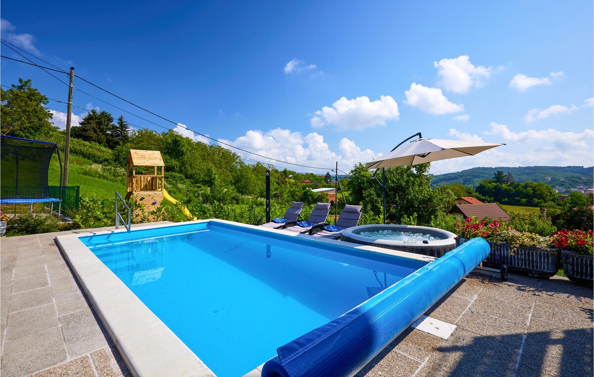 A private swimming pool is visible, surrounded by a spacious patio area. Comfortable lounge chairs are positioned nearby, and an umbrella offers shade. Lush greenery and distant hills frame the scene, contributing to a peaceful outdoor setting ideal for relaxation.