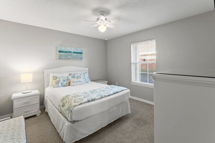 Chumba cha kulala cha wageni chenye mwanga na furaha chenye kitanda cha kifalme, mapambo ya ufukweni na zulia laini, kizuri kwa mapumziko ya usiku.