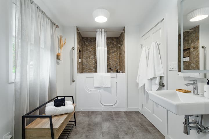 Baño de la planta principal con ducha y bañera para personas con discapacidad. 