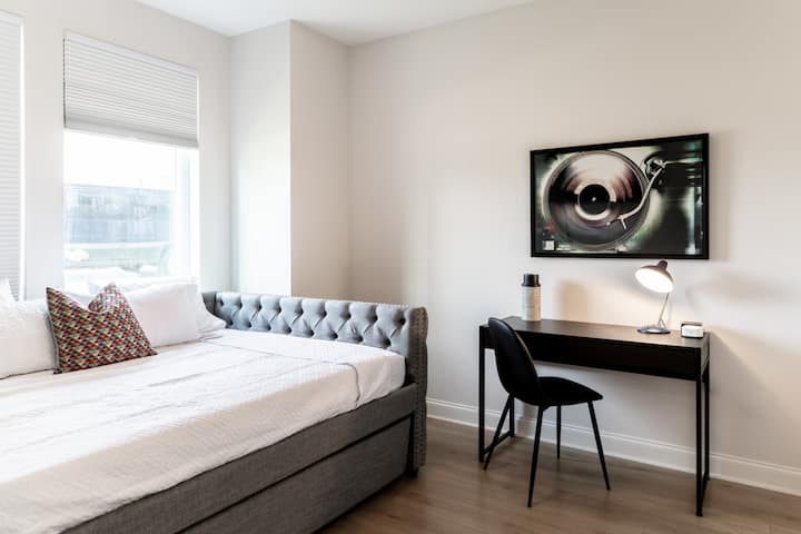 غرفة نوم للضيوف في الطابق الأرضي بسرير بحجم ملكي وسرير متحرك مزدوج ومساحة عمل وتلفزيون. حمام داخلي كامل الحجم متصل بغرفة النوم هذه.