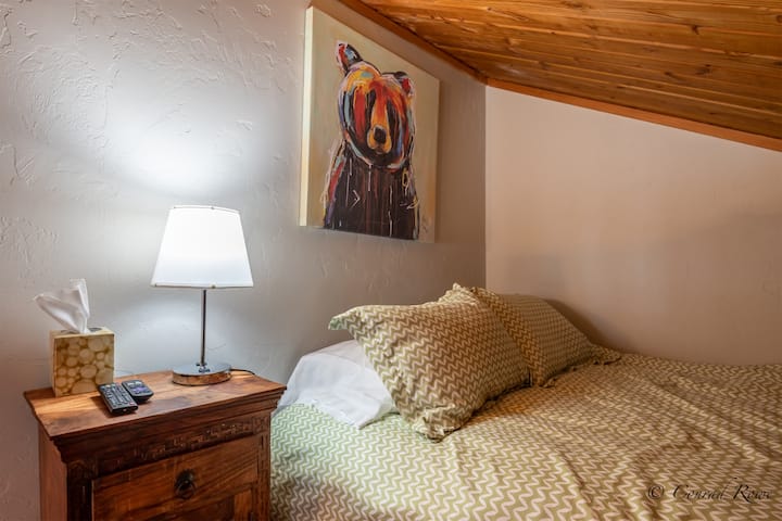 חדר שינה בלופט עם מיטה זוגית וטלוויזיה קטנה לבידור