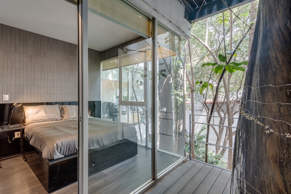 标准双人床，带露台和绿树成荫的景观。