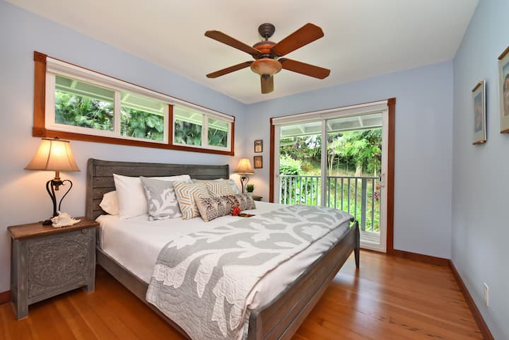 غرفة نوم هادئة مع سرير كينج وإضاءة طبيعية وإطلالات على الحديقة وديكور مستوحى من المناطق الاستوائية.