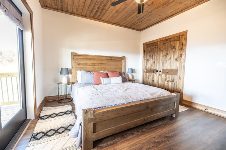 Მეორე მთავარი სართულის საძინებელი დიდი საწოლით და 50-დუიმიანი ტელევიზორით.