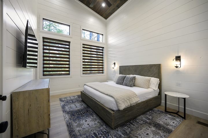 Dormitorio privado tamaño king con vistas a los árboles y ropa de cama de apoyo pero acogedora