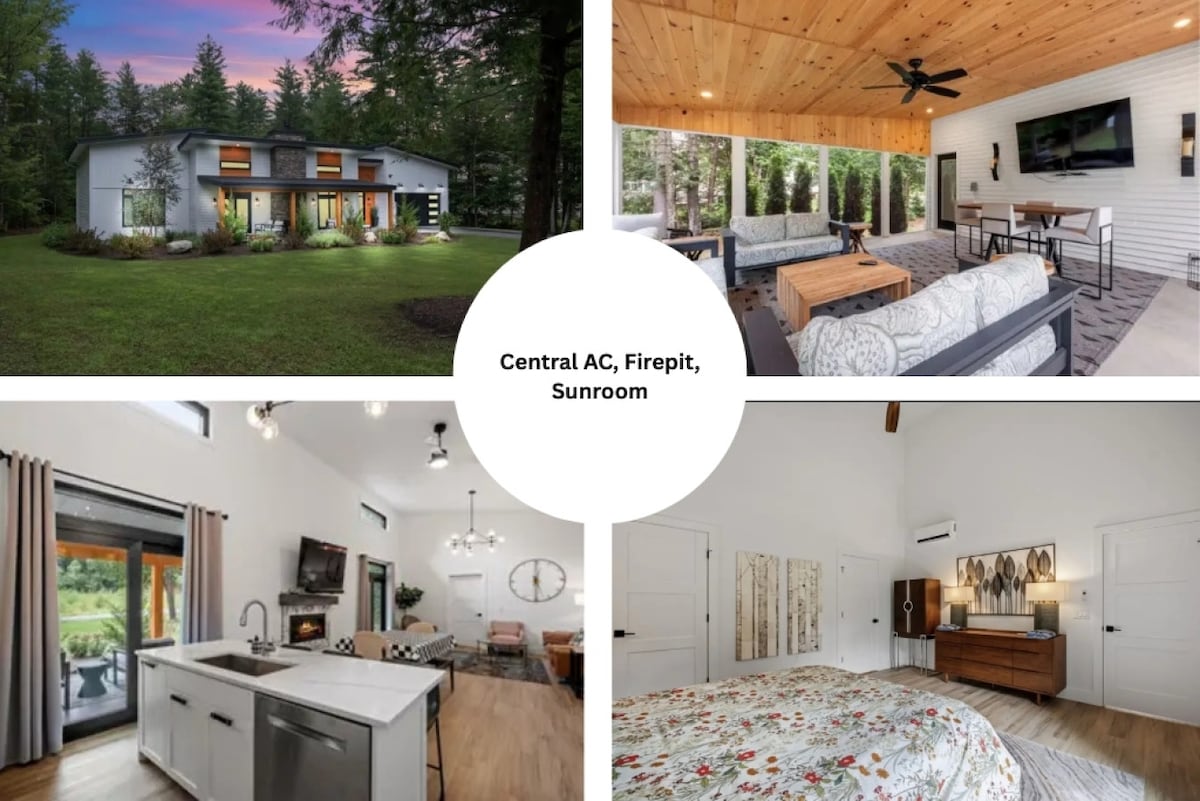 A modern home surrounded by trees features large windows, allowing natural light to illuminate the living spaces. The outdoor sunroom is furnished for relaxation, while the interior kitchen is equipped with modern appliances. A spacious bedroom with soft bedding provides comfort for a restful stay.