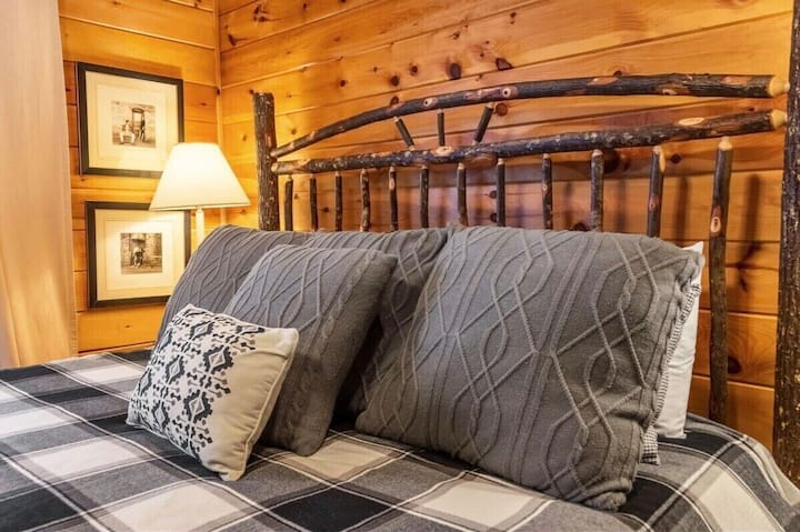 A large, plush bed with soft linens promises restful nights, while the cabin’s rustic décor adds a warm and inviting touch.