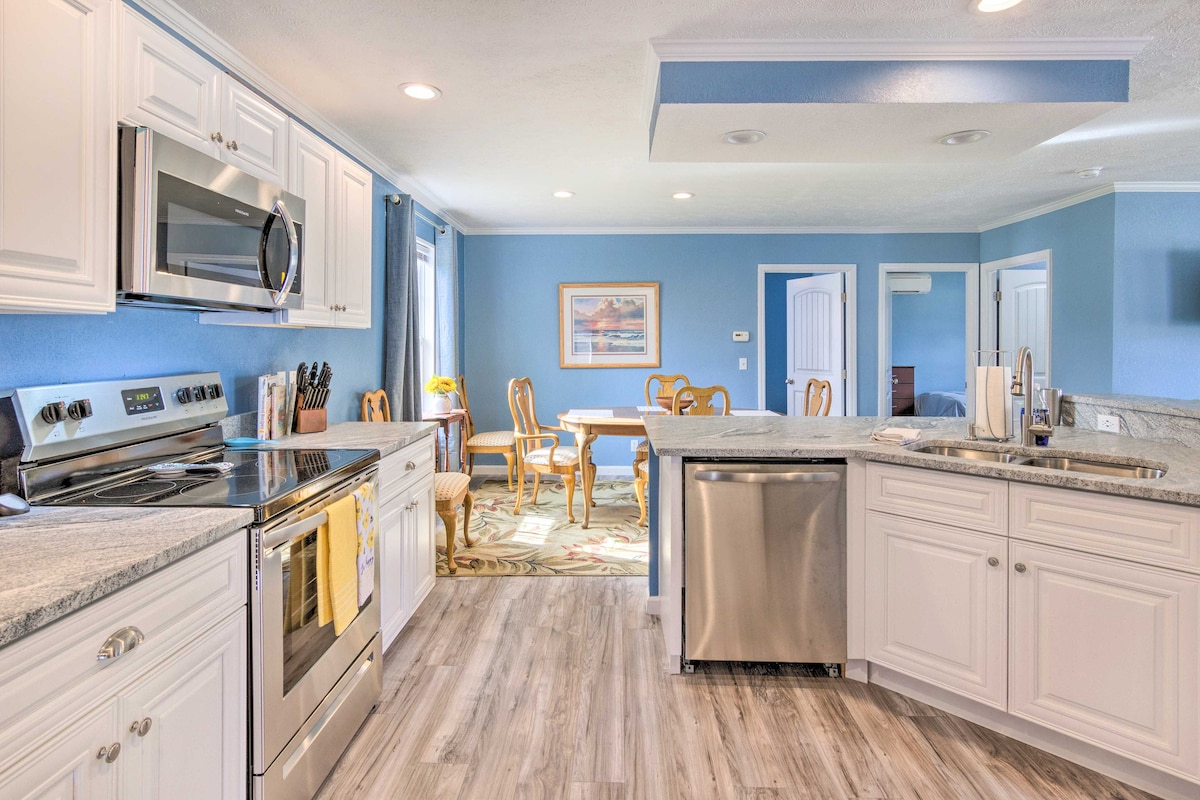 A spacious kitchen area is highlighted by stainless steel appliances and granite countertops. White cabinetry offers ample storage, while a dining area with wooden chairs is visible in the background, creating an inviting atmosphere for family meals.