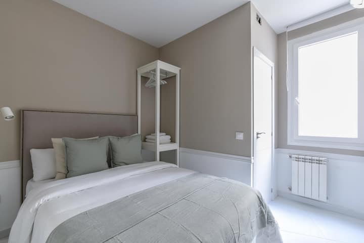 Поглед кон една од спалните соби со двоен кревет, мебел за шкафови и надворешен прозорец