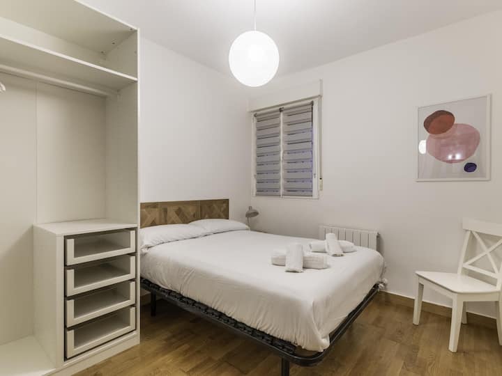 Amplia habitación con una cama doble, zona de almacenaje y un gran espejo.