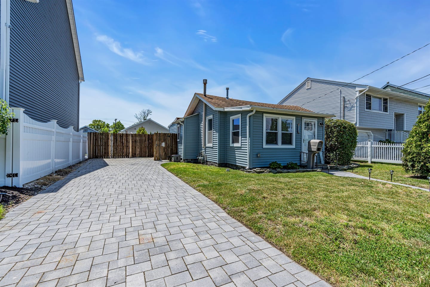 Pull into your own paver driveway. Single-story blue bungalow, no shared walls, no upstairs stomping. The kind of place you'll want to book again next summer.