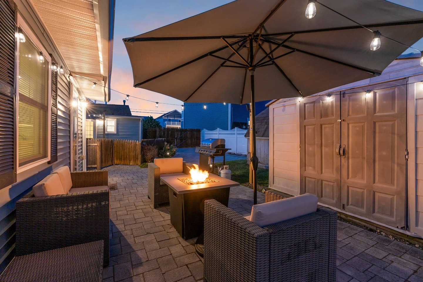 Pull up to the fire after a long beach day. Wicker lounge sectional, umbrella deployed, gas firepit already throwing heat. Phones can stay inside.