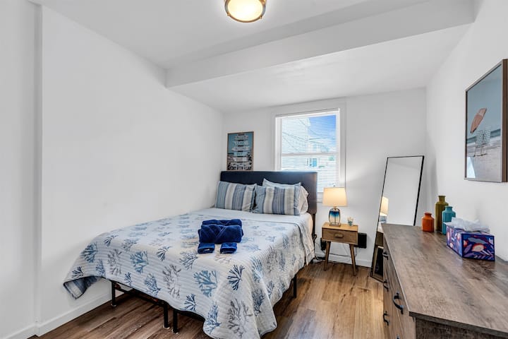 The queen room with coastal blue and coral bedding, a memory-foam queen bed and surfboard-print art