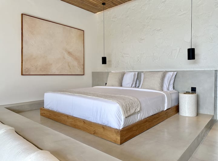 A refined bedroom featuring a plush king-size bed, a large built-in closet, and a private ensuite bathroom, enhanced by warm wooden details and natural light.