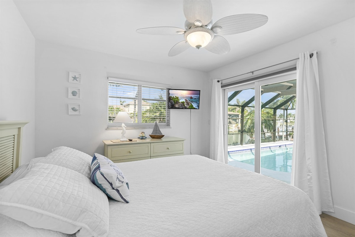 Relax in the Second Bedroom with Convenient Pool Access and Captivating Views of the Tranquil Canal.