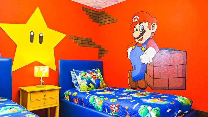Livligt rum med Mario-tema, färgglada väggmålningar, mysiga sängar och rolig inredning.