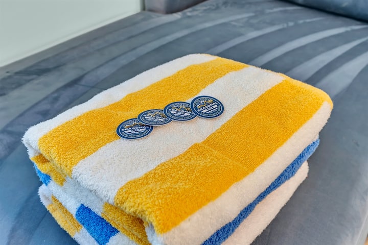 Four Ocean Grove seasonal beach badges and striped towels folded and ready for guests