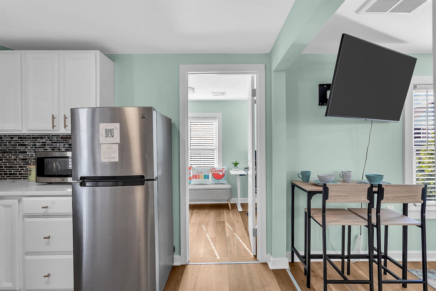 This bright and modern kitchen nook blends functionality with style, offering a cozy dining spot, sleek appliances, and a peek