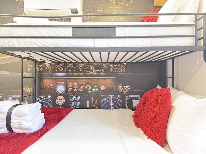 Chambre avec lits superposés, literie rouge et accents en bois.