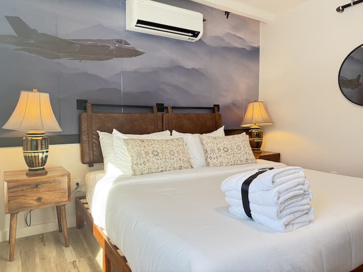 Chambre à coucher confortable avec éclairage par lampe et œuvres d'art représentant des montagnes.
