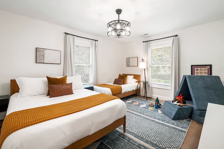 غرفة نوم بسرير كوين وسريرين صغيرين مع حمام في الردهة