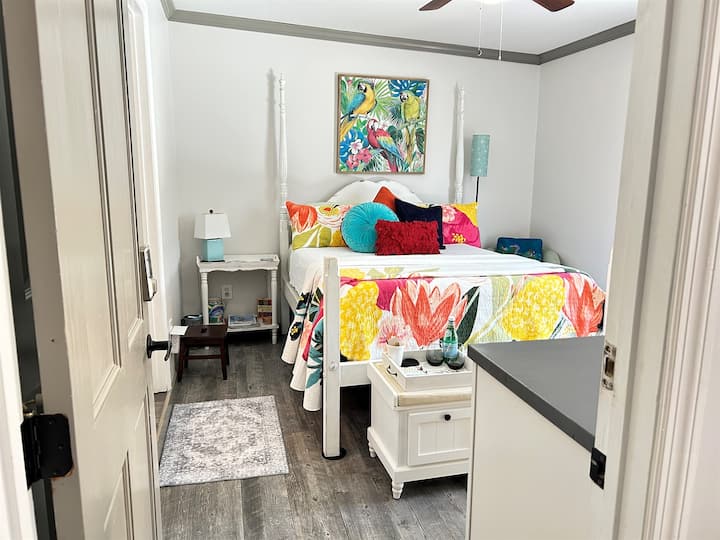 The 2nd primary suite features t its own en suite bathroom, tropical artwork, queen size four-poster bed, with upbeat sunny boho theme near downtown Pensacola