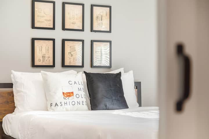 A cozy and rustic bedroom featuring a charming barn door and whiskey-themed decor, creating a warm and inviting atmosphere that is both stylish and unique.