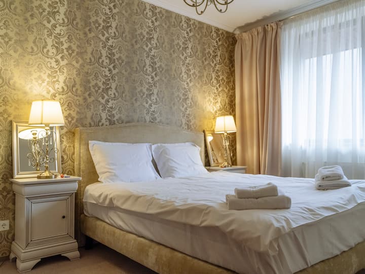 Amplio dormitorio con una cómoda cama tamaño queen, papel tapiz de estilo vintage y lámparas de noche para un ambiente tranquilo y acogedor, wifi de alta velocidad, calefacción