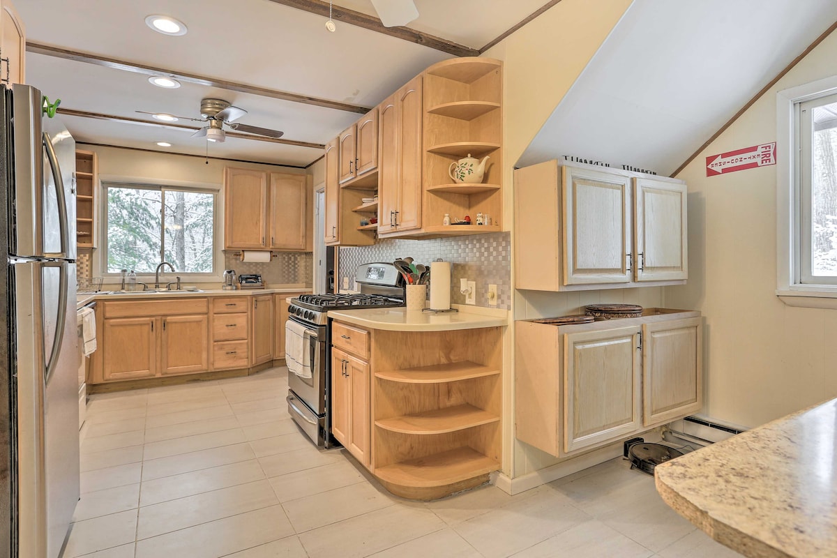 The kitchen features wooden cabinetry and stainless steel appliances, including a gas stove and refrigerator. Ample counter space is provided, with a well-organized layout. Natural light enters through the windows, while a ceiling fan offers ventilation.