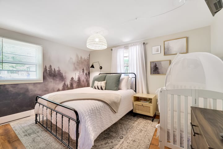 Descansa tranquilo en el dormitorio Evergreen con cama tamaño queen con sábanas de lujo ( Brooklinen) , cuna de tamaño completo para tu pequeño, escritorio y silla.