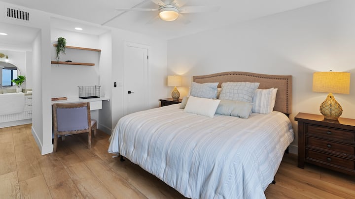 在宽敞的主卧套房中放松身心，配有舒适的加大双人床和带书桌和椅子的专用工作空间