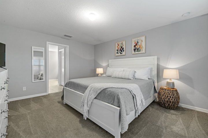 Primary bedroom with king bed, 2 walk-in closets, smart flatscreen TV and ensuite bathroom with tiled shower.