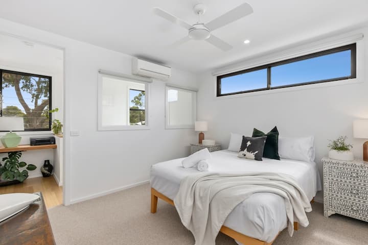 El dormitorio principal de arriba cuenta con cama tamaño queen, baño privado, aire acondicionado y vistas tranquilas de los árboles de goma circundantes.