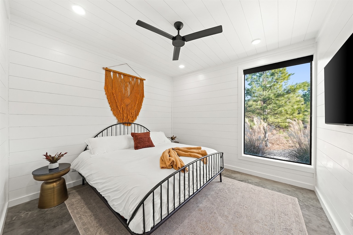 Dormitorio con encanto: espacio iluminado por el sol con una cama elegante, una decoración moderna y vistas panorámicas a la naturaleza.