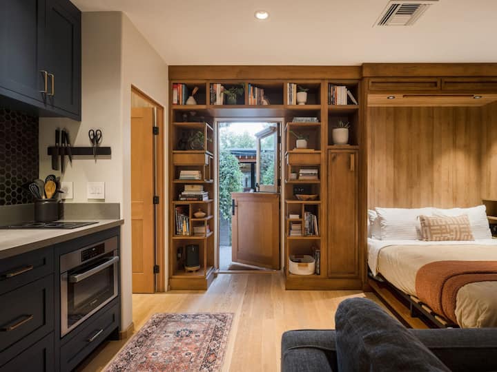 อ่านหนังสือ เล่นเกม หรือฟังเพลงจากลำโพง Sonos — ทุกอย่างอยู่ในชั้นวางของบนผนังห้องสตูดิโอ ผ้าห่มเสริมหลังประตูเตียงทำให้ง่ายต่อการทำตัวสบายหลังจากสำรวจเทมเปและอื่น ๆ