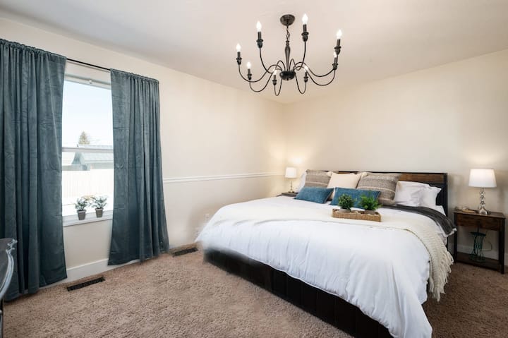 Relájate en este espacioso dormitorio tamaño king con iluminación suave, decoración elegante y ropa de cama lujosa, perfecto para una noche de sueño tranquilo cerca de Salt Lake City.