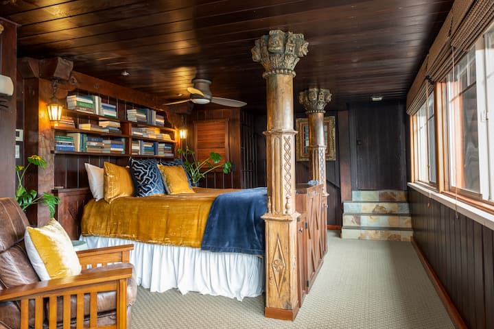 Downstairs, the master bedroom has a king bed with curious, custom wood columns, and fun books.