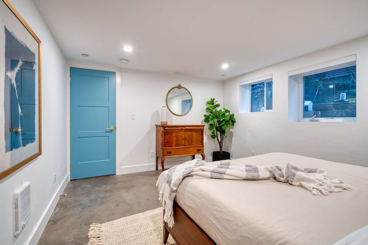 Bedroom with a wooden bed frame, dresser and blue door.