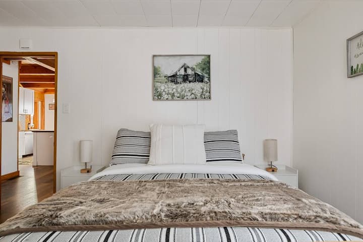 El dormitorio principal tiene una cama queen y ropa de cama cómoda.