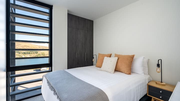 Mit einem gemütlichen Queensize-Bett und einer schönen Aussicht auf den See und die Berge bietet das zweite Schlafzimmer einen ruhigen Rückzugsort mit einem Hauch von Luxus.