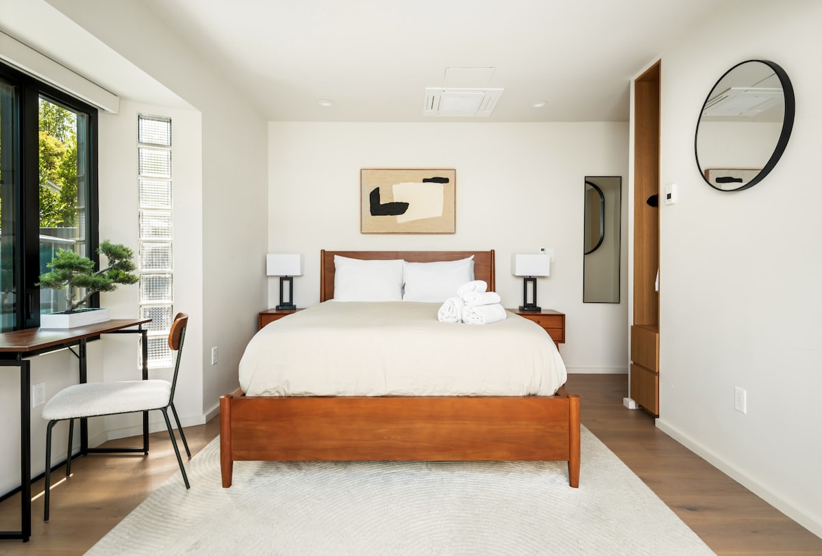Bright, clean, and cozy—this queen bedroom offers a relaxing retreat with natural light and a dedicated desk for work or study during your stay.