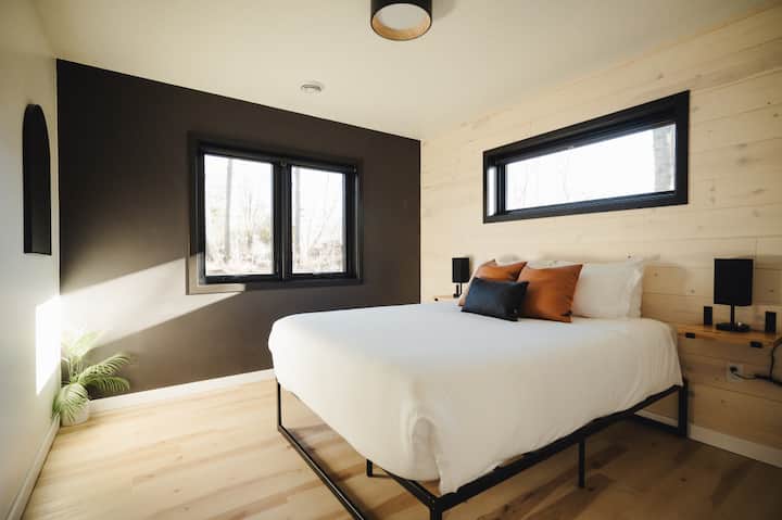 Მყუდრო საძინებელი, რომელშიც დგას ორადგილიანი საწოლი, თანამედროვე სკანდინავიური სიმარტივით, დამამშვიდებელი, კომფორტული დასვენებისთვის