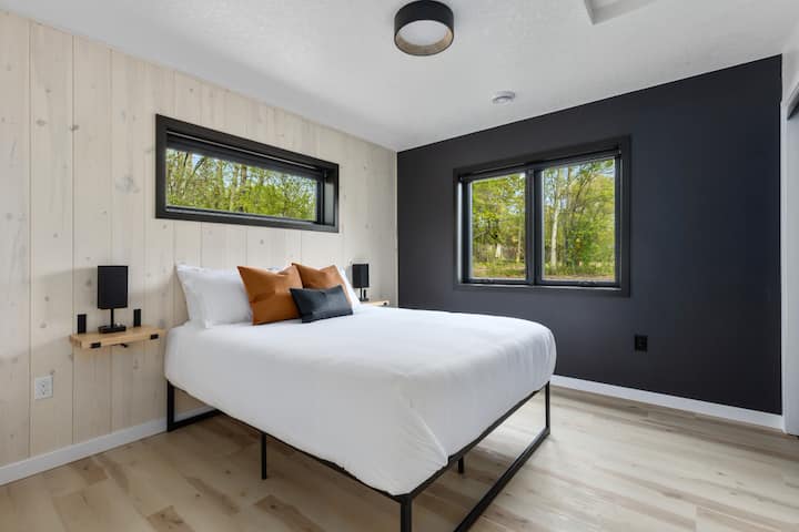 Მყუდრო საძინებელი, რომელშიც დგას ორადგილიანი საწოლი, თანამედროვე სკანდინავიური სიმარტივით, დამამშვიდებელი, კომფორტული დასვენებისთვის