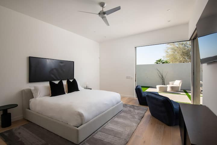 One of the tranquil bedrooms, featuring a comfortable bed, large smart TV, and private access to the beautifully landscaped yard.
