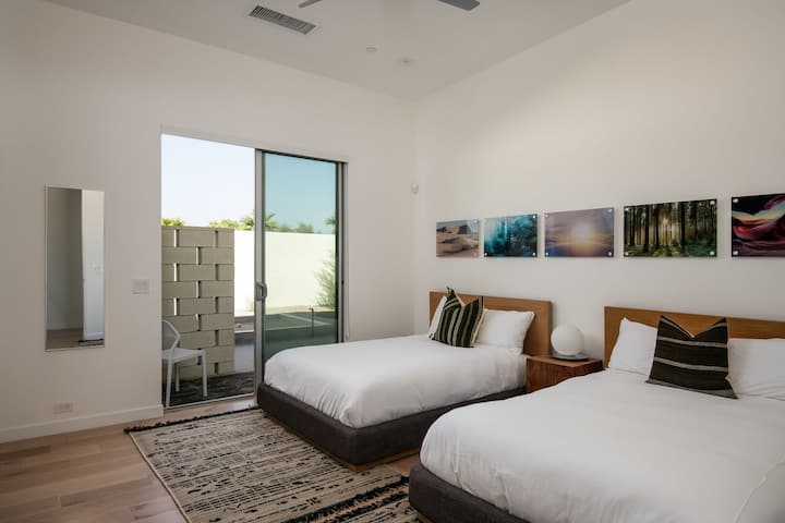 The Twin Bedroom offers two comfortable beds, stylish decor, and direct access to a quiet outdoor patio area.