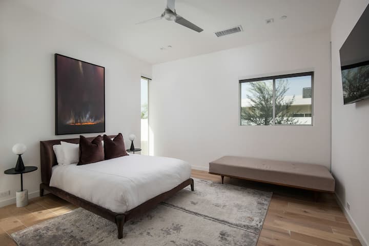 बड़े प्राइमरी गेस्ट सुईट में एक शानदार क्वीन बेड, आधुनिक कलाकृतियाँ और एक आरामदायक शेज़लॉन्ग है।