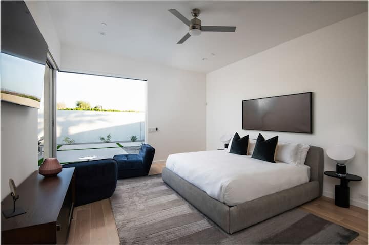 La espaciosa suite principal ofrece una cama tamaño king, una zona de estar y una gran pared de ventana que invita a la luz del sol del desierto.