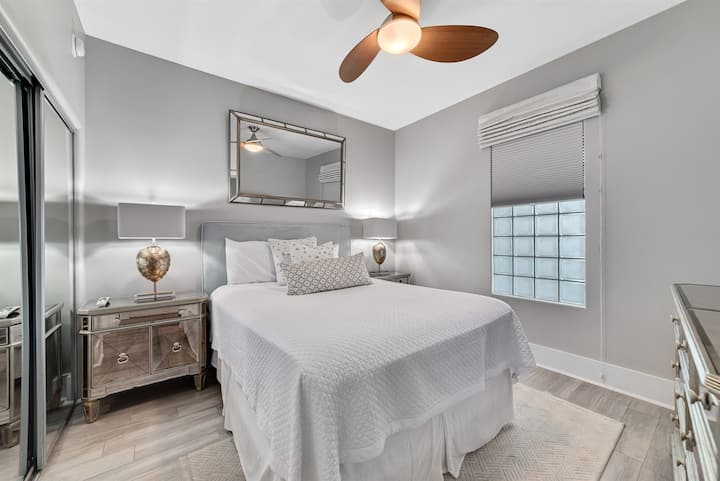 سرير مريح متوسط الحجم مع بياضات بيضاء واضحة، تحيط به طاولات جانبية ومصابيح متطابقة، مما يوفر مساحة مريحة وجذابة.